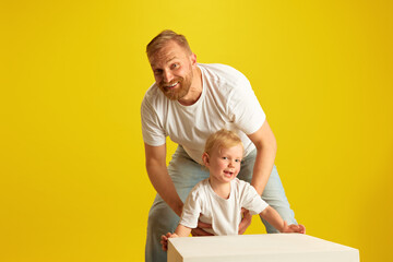 Family playtime. Father and his young son full of joy in middle of exciting game against yellow...