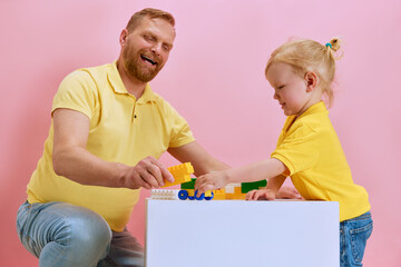 Creative Block Building. Dad and his son deeply engaged in building toy with vibrant blocks against...