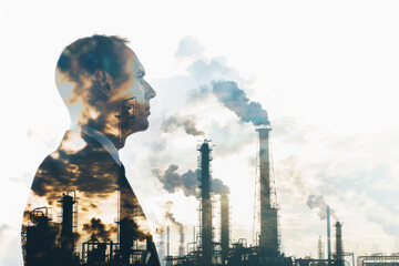 Industrial Vision: Businessman and Factory Double Exposure. A powerful double exposure image combining a contemplative businessman with the dramatic silhouette of a smoke-emitting industrial factory.