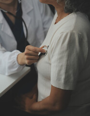 Doctor using sphygmomanometer with stethoscope checking blood pressure to a patient in the hospital.