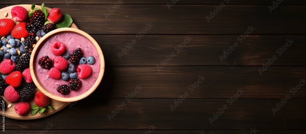 Poster A top down view of a wooden table showcasing a bowl filled with raspberry smoothie and an assortment of berries leaving space to add text or images. with copy space image