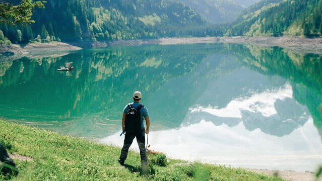 A man went on a trek around a mountain lake with a corgi dog