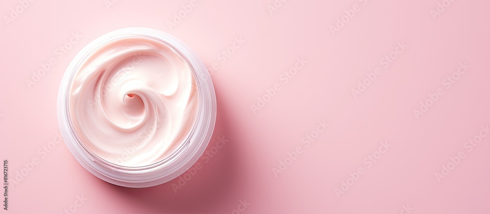 Poster Top view of a moisturizer with a half opened lid placed on a light pink background in a flat lay style with copy space image