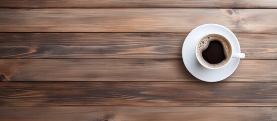 Top view of a white coffee cup on a wooden table with plenty of empty space surrounding the cup for a copy space image