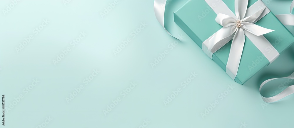 Poster copy space image of a top view flat lay featuring a white gift box adorned with a tiffany satin ribb