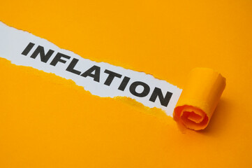 White surface, with the word Inflation in black, underneath torn and rolled yellow cardboard.
