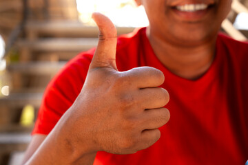 Closeup of a young latin man pointing thumb up. Confident facial expression.