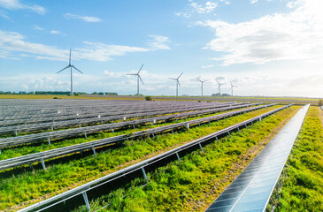 Wind turbines and solar panels farm in a field. Renewable green energy. Sunny landscape, electric energy generator for clean energy producing concept. Solar panels and wind power generation equipment