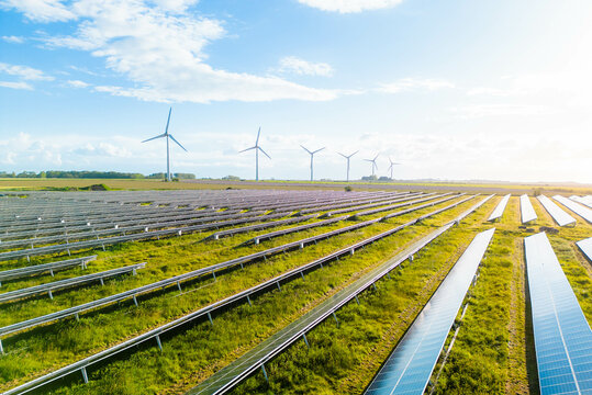 Wind turbines and solar panels farm in a field. Renewable green energy. Sunny landscape, electric energy generator for clean energy producing concept. Solar panels and wind power generation equipment