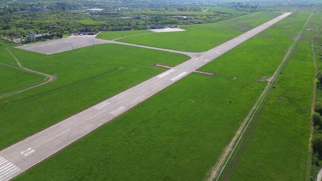 Aerial footage of rural airport runway taxiway and ramp. Airfield tarmac seen from above. Airstrip flyover during a sunny summer day. Instrument landing system on a landing strip. Aerodrome. Bulgaria
