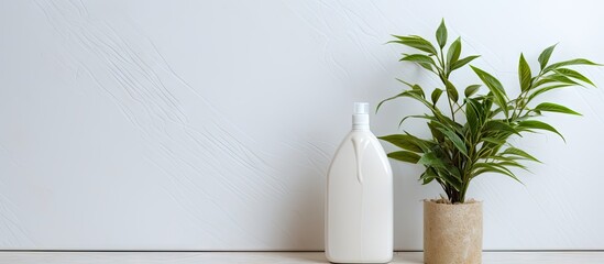 A white tile background with a beige bottle of laundry detergent and a green plant Copy space...