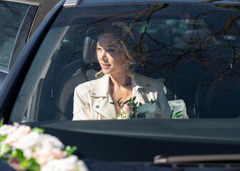 Wedding photo of the bride in the car through the glass