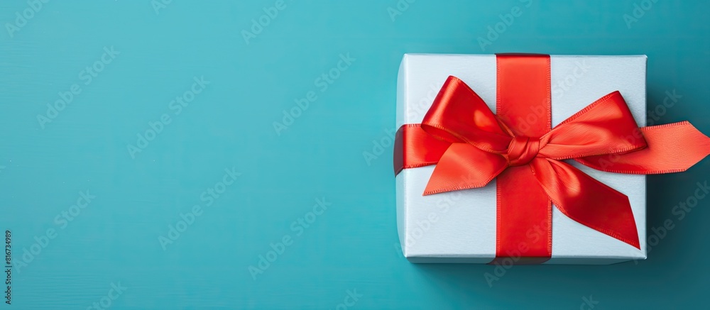 Aufkleber Top view of a gift box with a red bow on a blue background serving as a holiday background Perfect for copy space image