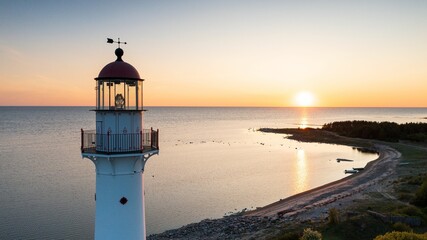 Aerial view to the top of the historic lighthouse on the setting sun background at the Baltic Sea