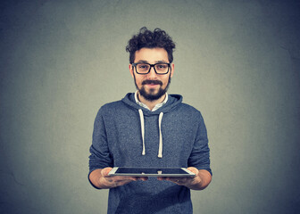 Handsome hipster guy with a tablet computer looking at camera  