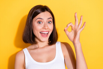 Photo of funky excited lady dressed white top smiling showing okey sign isolated yellow color...