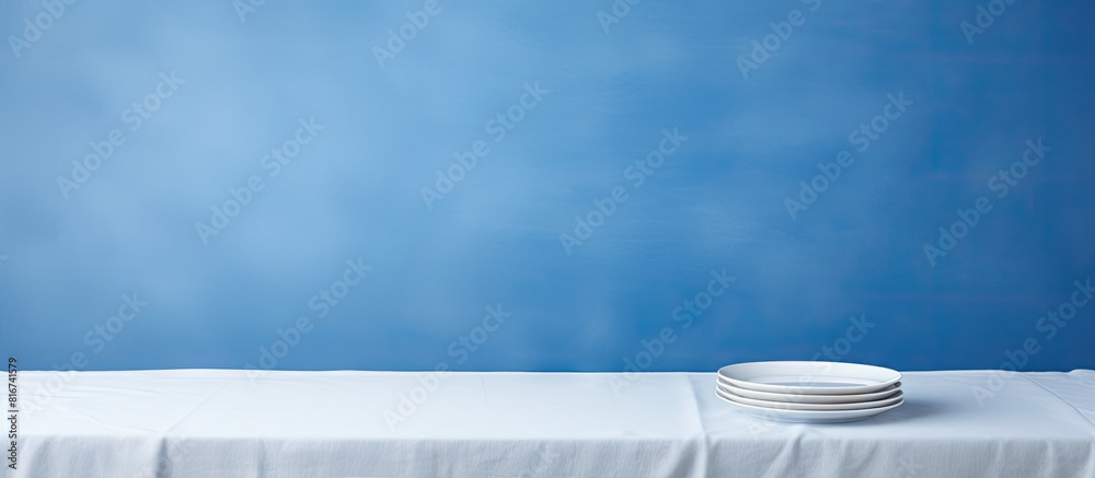 Aufkleber Copy space image of a white wooden table with a new blue tablecloth featuring an empty plate on top