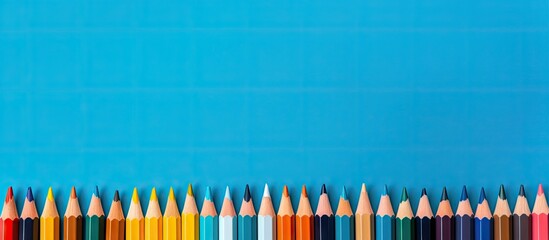 A copy space image for art school or back to school featuring color pencils laid out on a blue background