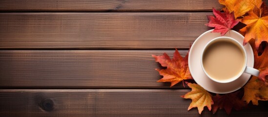 Top view of autumn maple leaves book and coffee cup on a wooden surface with copy space image