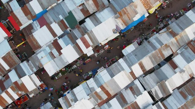 Bird's eye drone footage of people walking in a road in a local market at sunset in Arusha, Tanzania