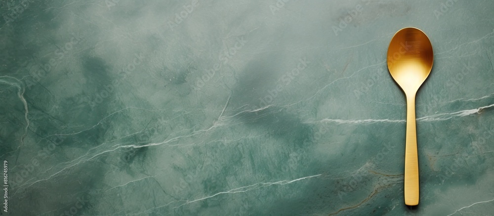 Poster Top view of a minimal style gold frame and square complemented with a wooden spoon placed on a green marble background The image provides ample text space