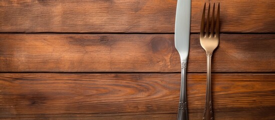 A copy space image of a vintage fork and knife on a wooden background texture suitable for...