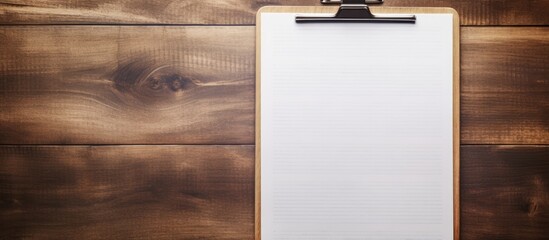 A vintage style image shows a wooden background with a clipboard featuring a white sheet on top...