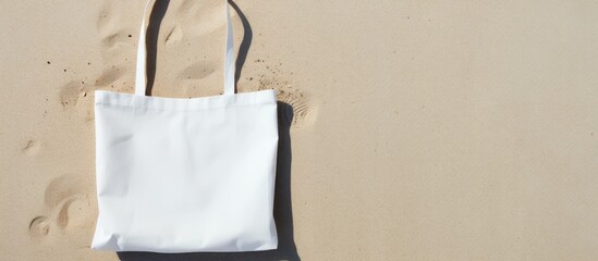 Flat lay on a beach sand background featuring a white cotton or mesh bag The bag represents a zero waste eco friendly shopping and recycling concept It is a blank mockup shopper with copy space for a