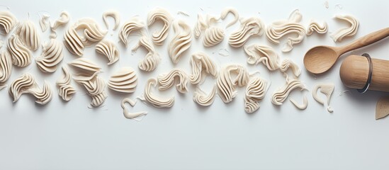 A composition featuring a copy space image with cookie cutters a whisker and a rolling pin on a white textured wooden surface as seen from above - Powered by Adobe