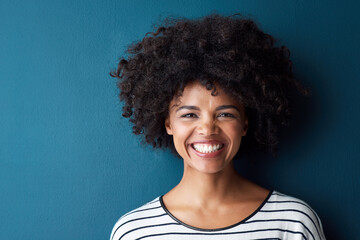 Black woman, portrait and smile with funny, glow and confident on blue studio background. Girl,...