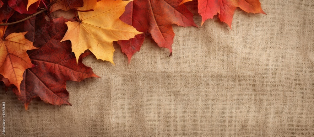 Poster autumn leaves in vibrant colors are showcased against a textured burlap background providing ample c