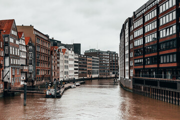 Scenic view of a river flowing alongside a row of buildings with red-tiled roofs in Hamburg