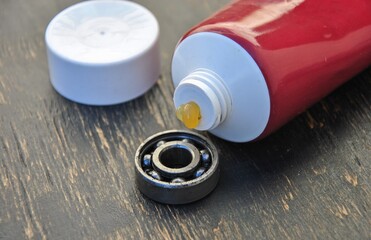 bearing lubrication. bearing and tube of lubricant on a wooden background. selective focus