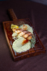 Grilled salmon fillet with lemon and herb butter on a wooden board