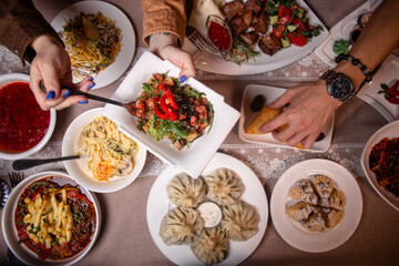 A table with delicious Uzbek dishes like soup, salad, dumplings, and meat skewers, offering a taste...