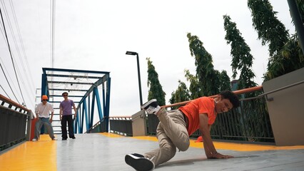 Skilled happy hipster perform footstep at bridge with low angle camera. Break dancer practice b-boy...