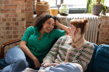Two young adult friends laughing together in a shared loft apartment
