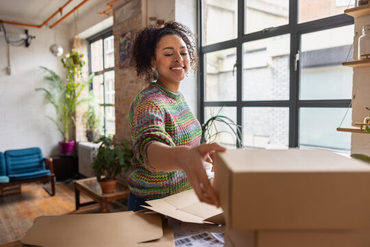Female entrepreneur packing orders into cardboard boxes to ship
