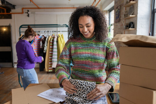 Young female vintage fashion business owner packing orders and preparing labels 