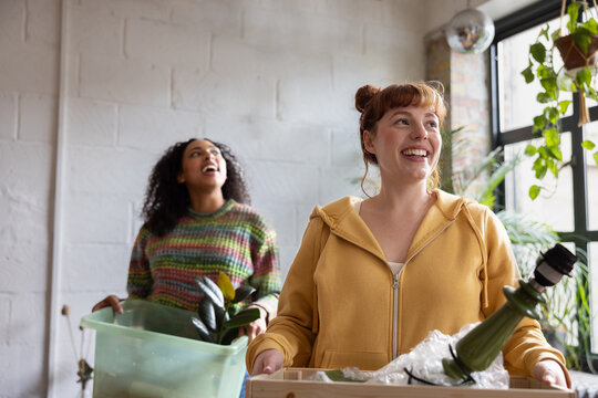 Two friends carrying boxes moving into a new home