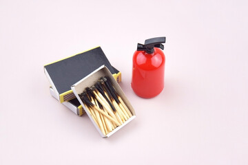 A box of matches placed next to a toy red fire extinguisher against a light background.