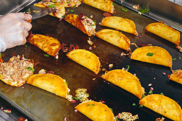 Frying tacos tortillas with cheese, onion, herbs and meat on griddle in professional kitchen in restaurant. Mexican cuisine, Latin American fast food