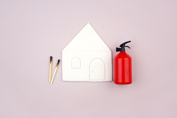 A box of matches placed next to a toy red fire extinguisher against a light background.