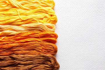 Threads of different shades of orange on white fabric. 