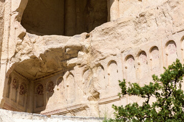 Close-up view of an ancient rock-hewn monastery in Cappadocia, intricate carved details and faded...