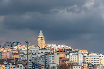 Dramatic view of Istanbul's skyline with the iconic Galata Tower standing tall against a backdrop of dark, stormy clouds. Istanbul, Turkey (Turkiye)