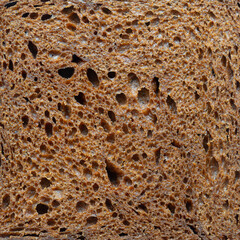 A close up of a piece of bread with holes in it. The bread is brown and has a rough texture