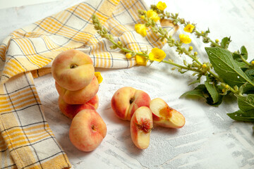 Halves and several whole saturn peaches or flat peach on white wooden background..
