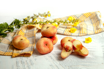 Halves and several whole saturn peaches or flat peach on white wooden background..