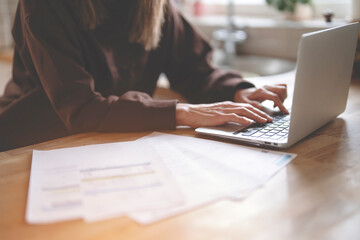 hands of woman using laptop, reading letter savings employment tax paying energy bill 